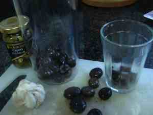 Depipping the olives using a glass.